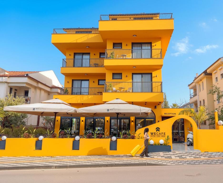 ein gelbes Gebäude mit einem Restaurant davor in der Unterkunft WeSuites in Fethiye