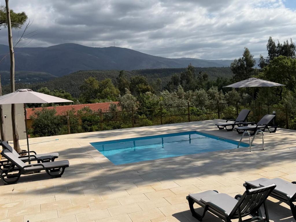 a swimming pool with lounge chairs and an umbrella at Quinta-lina de serpins in Serpins