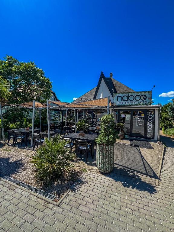 a restaurant with tables and umbrellas in front of it at Zöldház Panzió in Gyenesdiás