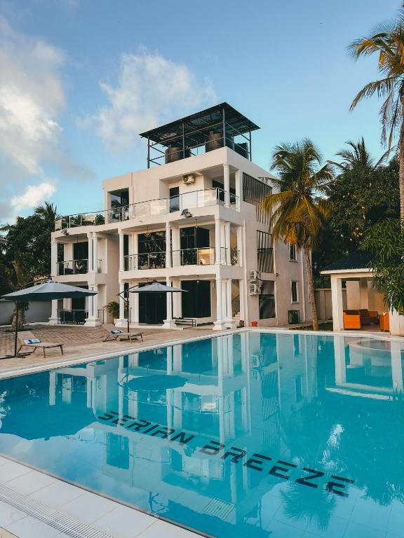 a building with a swimming pool in front of it at Serian Breeze 6 Bedroom Villa Diani in Ukunda