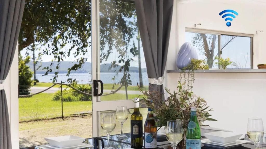 a table with wine glasses and a view of the ocean at Waterfront Cottage in New South Wales 
