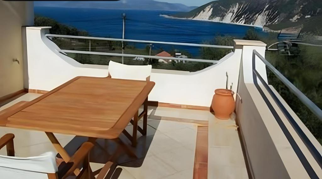 a balcony with a wooden table and a view of the ocean at Afales Villa and Studios in Exoyí