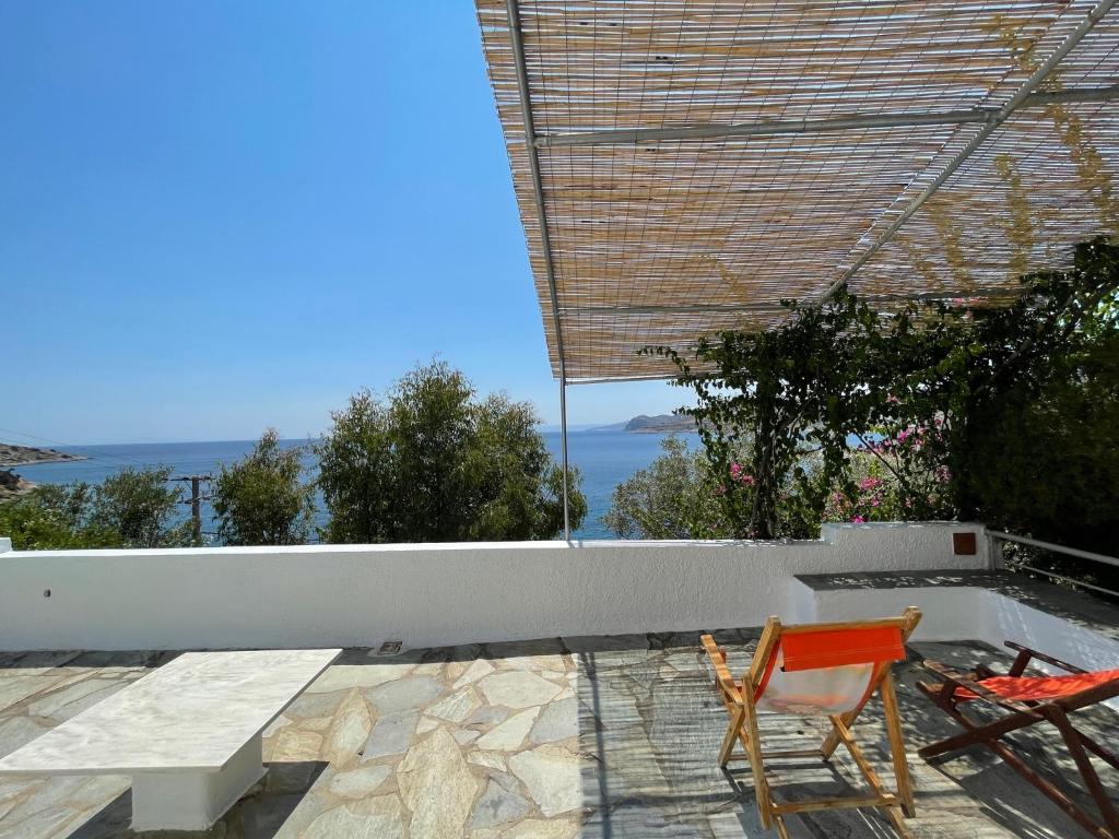 a couple of chairs sitting on a patio overlooking the ocean at Attica Vacation Home in Dhaskalión