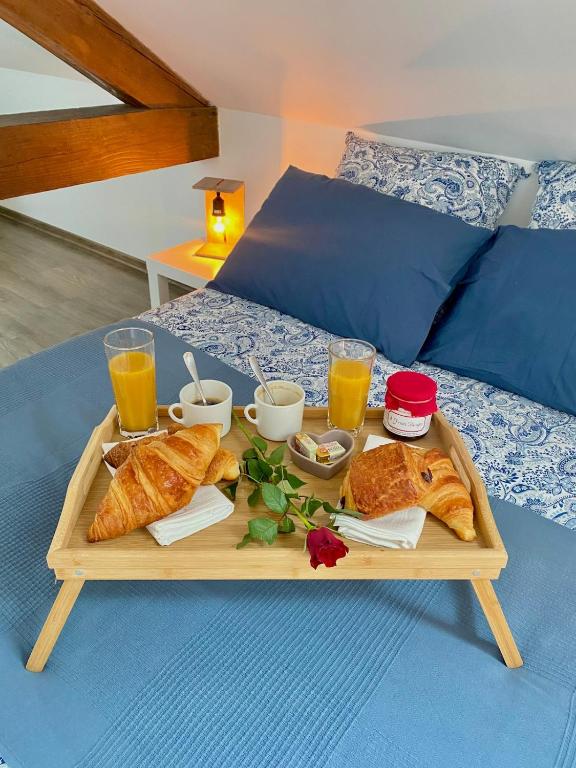 a tray of bread and croissants on a bed at Le secret du Morvan in Saulieu
