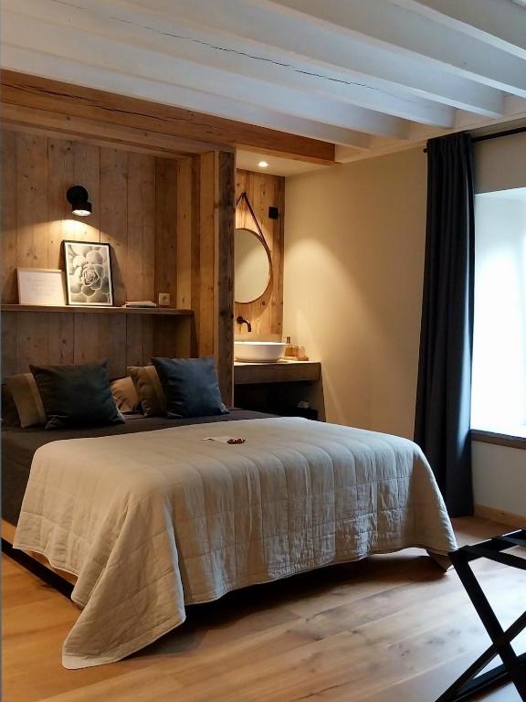 a bedroom with a large bed and a mirror at B&B En face du Marronnier in Cornimont