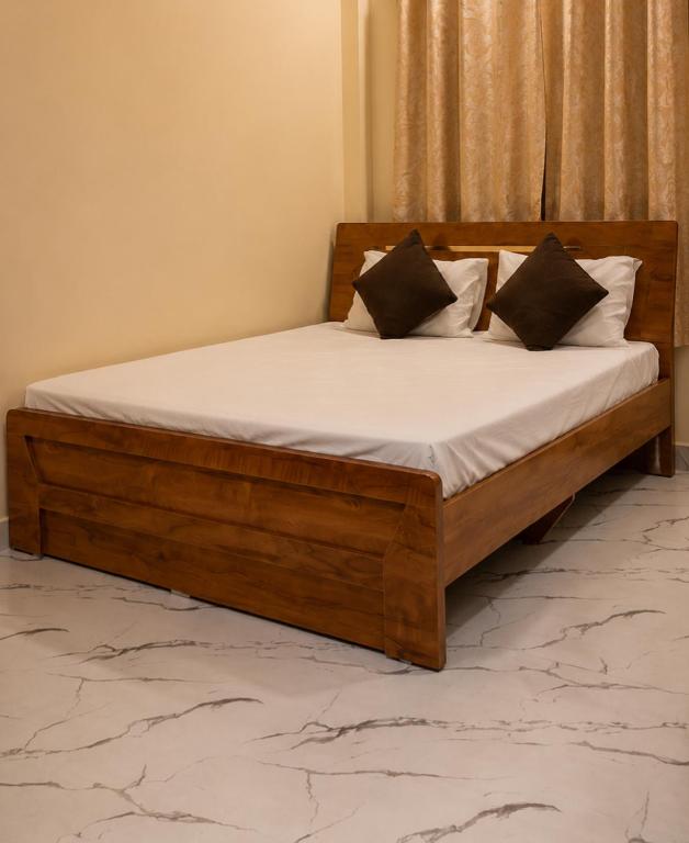 a wooden bed with white sheets and pillows on it at Thaanya Guest Rooms in Chinchwad