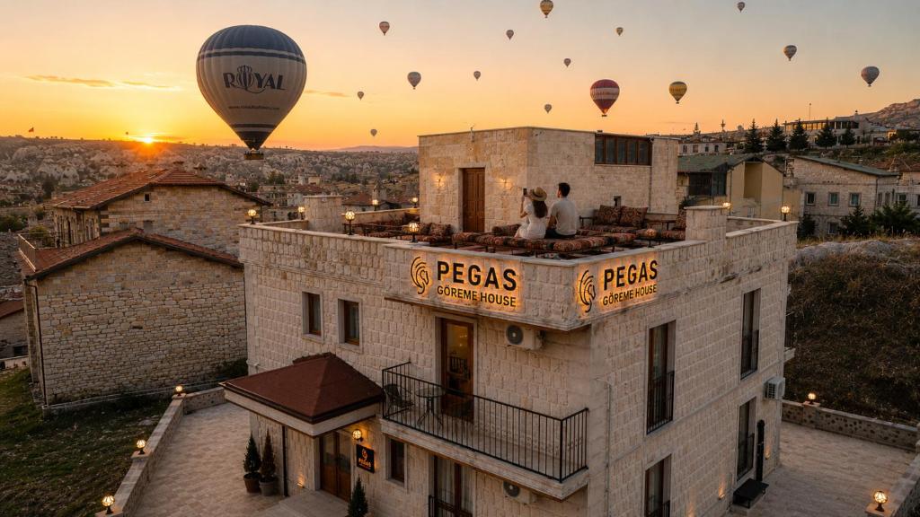 a group of hot air balloons flying over a building at Pegas Goreme in Göreme