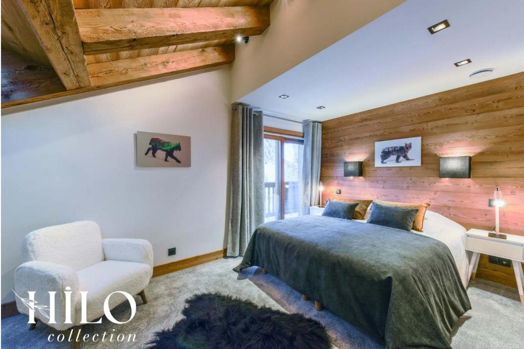 a bedroom with a king sized bed and a chair at Chalet Alya by HILO Collection in Les Allues