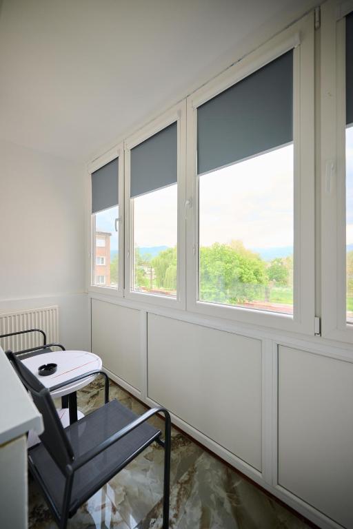 a table and a chair in a room with windows at Apartament Aleea Școlii in Haţeg