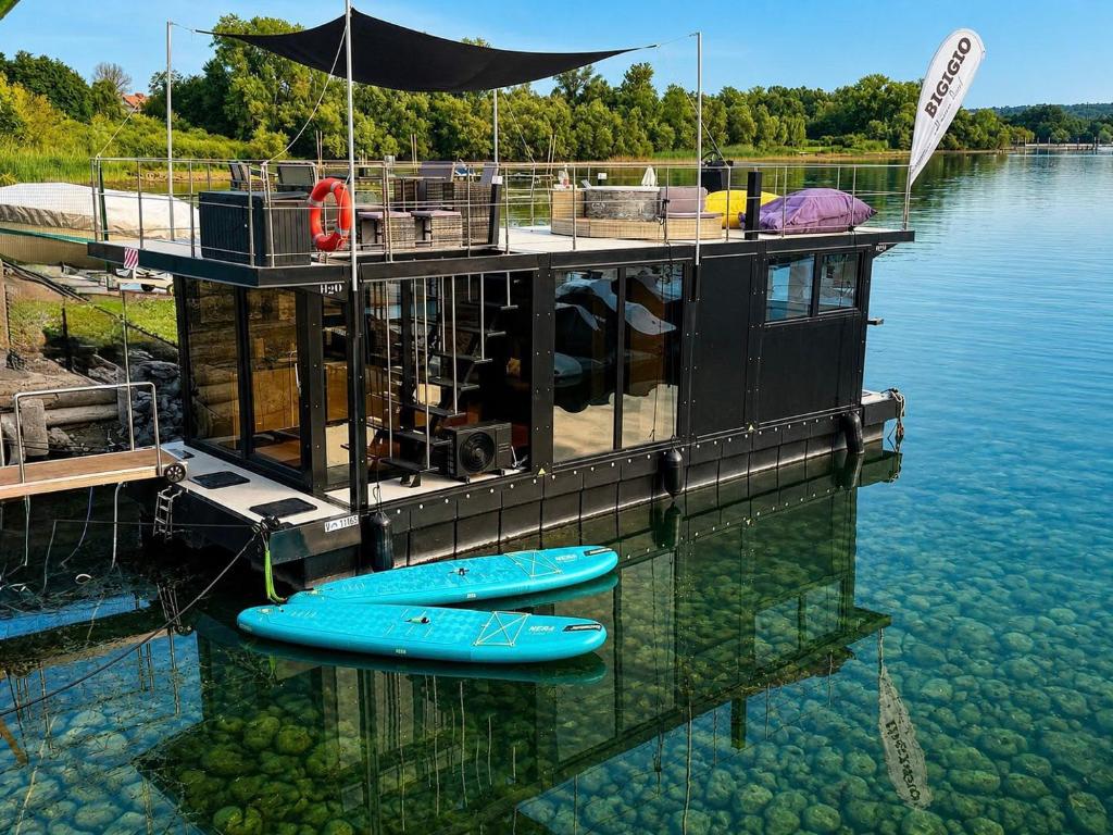 a floating house with two kayaks on the water at DIAMOND Bigigio House Boat in Lisanza