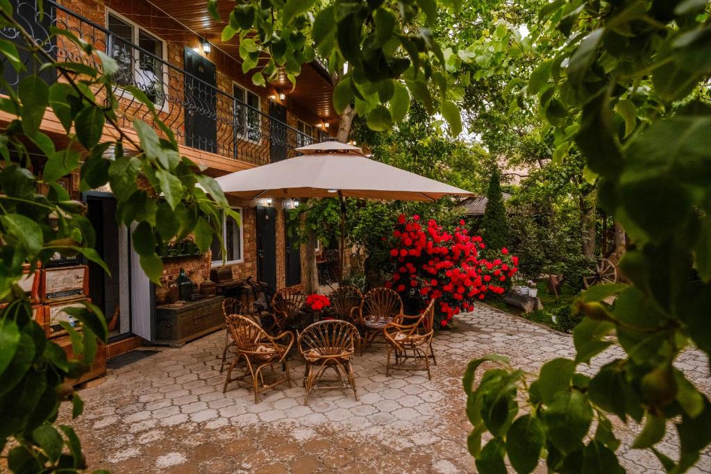 a patio with chairs and an umbrella and red flowers at Art Hotel Al Hayat in Kaji-Say