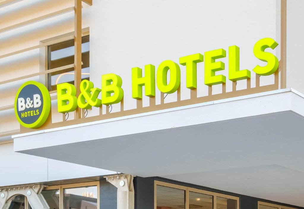 a sign for a bbq hotel on a building at B&B HOTEL Magnanville in Magnanville