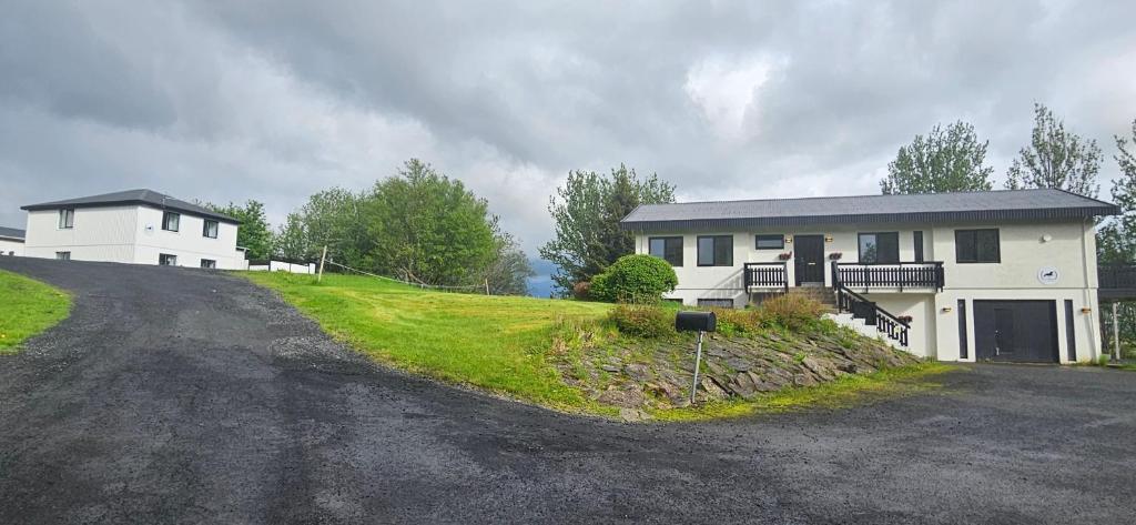 a white house on a hill with a driveway at Fellskotshestar Guesthouse in Selfoss