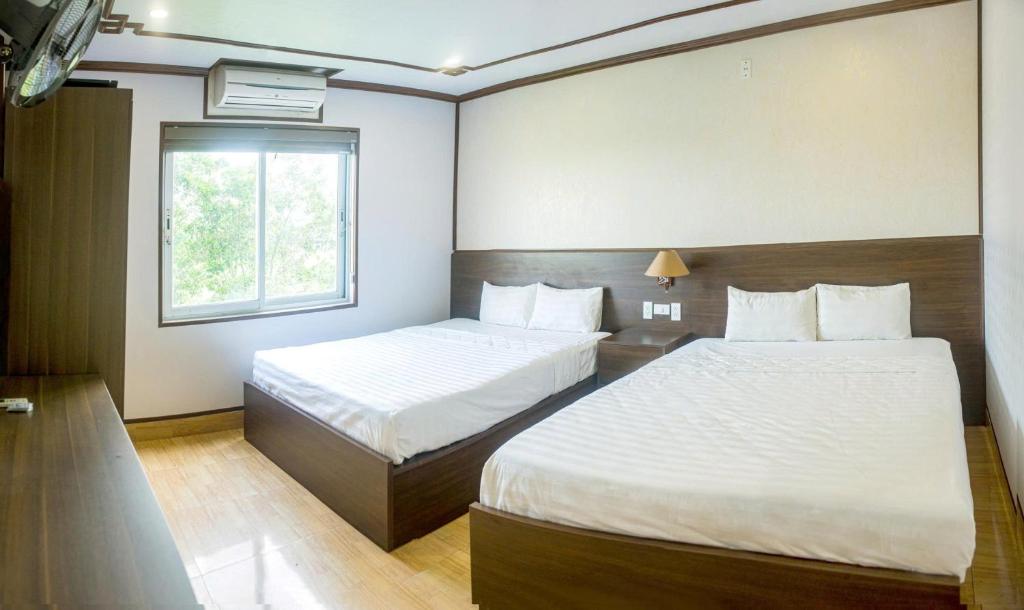 a hotel room with two beds and a window at Anh Duong Hotel in Noi Bai