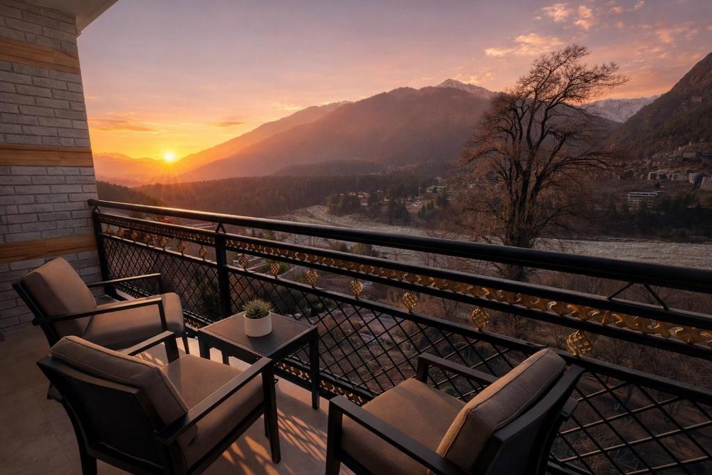a balcony with chairs and a table and a sunset at The Sana Cottge, Manali - Affordable Luxury Stay in Manali in Manāli