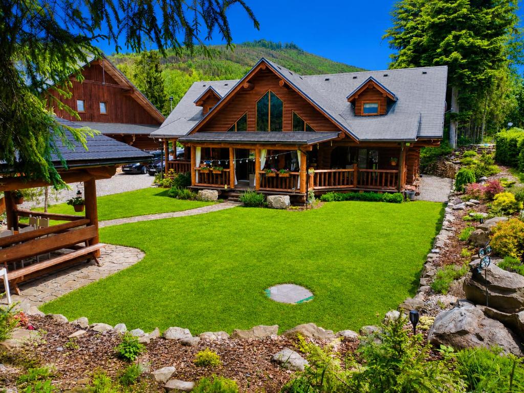a log home with a large yard of green grass at Chalet Velora in Oščadnica