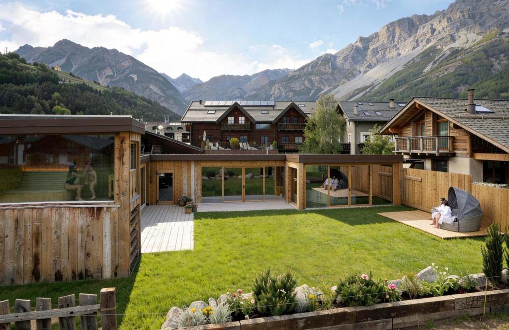 a house with a garden with mountains in the background at Agriturismo Rini in Bormio