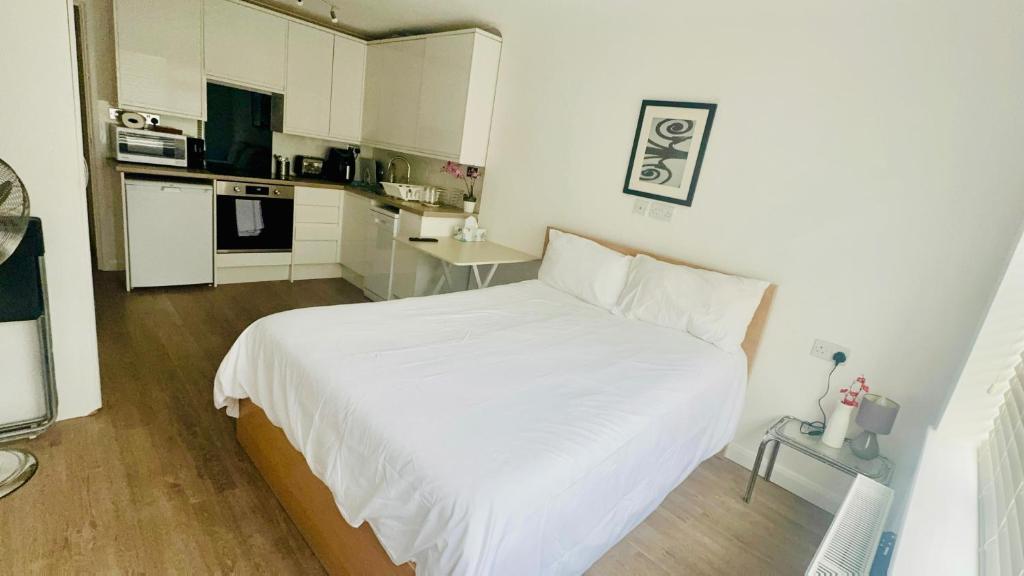 a small bedroom with a white bed and a kitchen at Studio - Sleeps 2 - Wifi - Parking in Dunstable