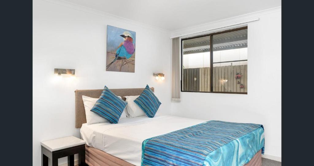 a white bedroom with a bed and a window at A&A Lodge Motel in Emerald