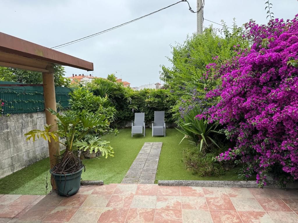 two chairs in a garden with purple flowers at Casa de Joaquina in O Grove