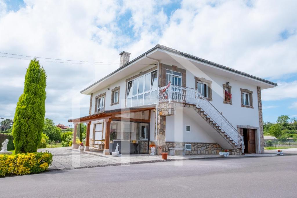 a large white house with a balcony and stairs at El Jardin de Pruvia in Llanera