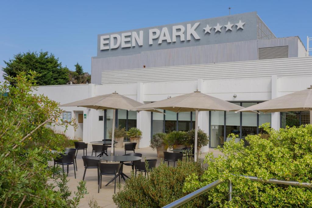 an outdoor patio with tables and umbrellas in front of a building at Hotel Eden Park by Brava Hoteles in Riudellots de la Selva