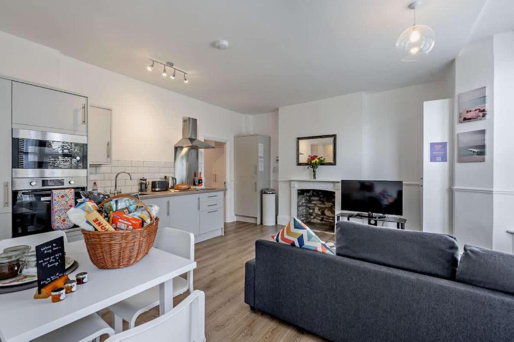 a living room with a couch and a kitchen at Dizzy Lows Modern 1 Bedroom Swanage Apartment with Sea View in Swanage