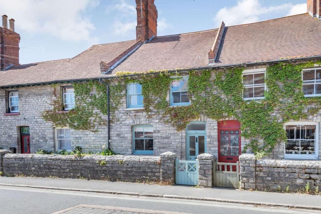 an ivy covered building with a red door at Passiflora Cottage Close to Swanage Beach and Town Sleeps 7 in Swanage