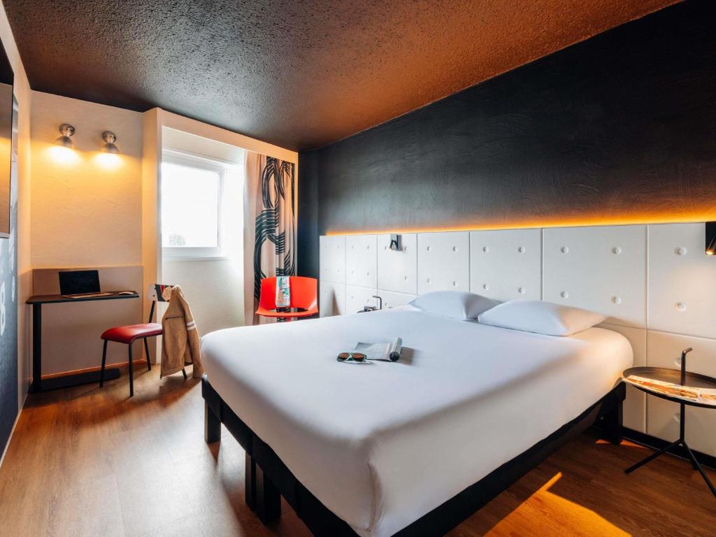 a bedroom with a large white bed with a black wall at ibis Styles Lyon Sud Vienne in Chasse-sur-Rhône