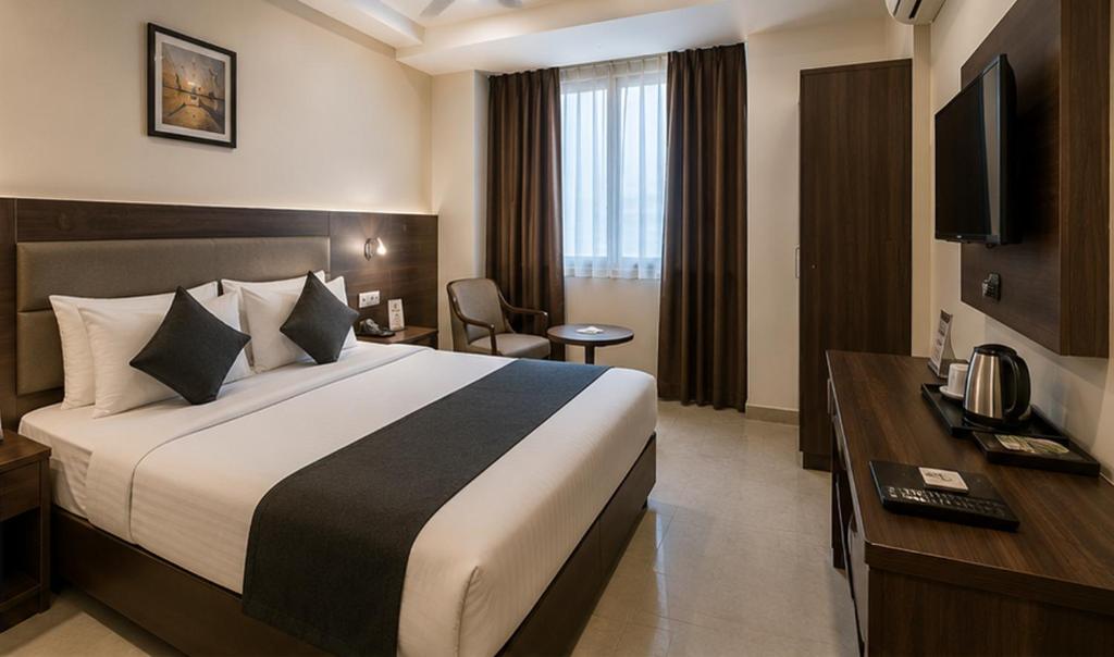 ein Hotelzimmer mit einem großen Bett und einem Fernseher in der Unterkunft Hotel Smart Snap Sector 104, Noida in Noida