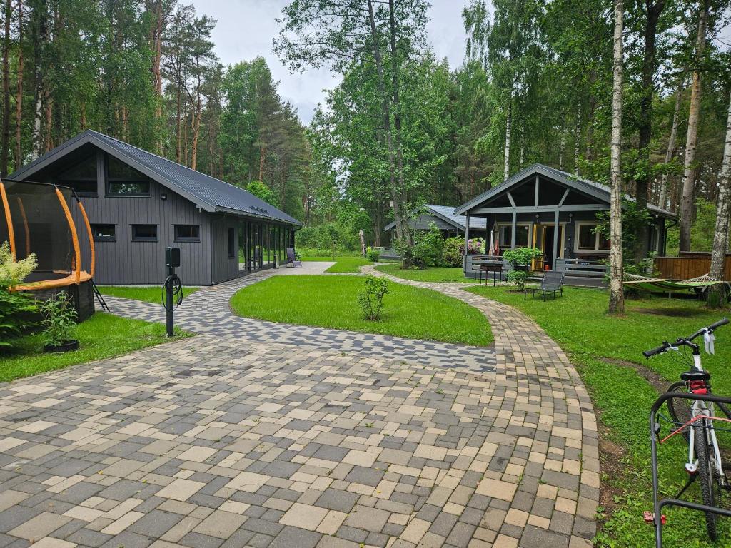 a cobblestone driveway leading to a building with a house at Pie Putniem in Lapmežciems