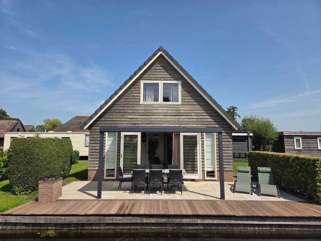 a house with a deck with chairs and a table at De Sloothaak in Giethoorn