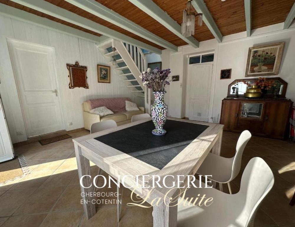 a living room with a table with a vase on it at Le Nid du Matelot in Saint-Vaast-la-Hougue