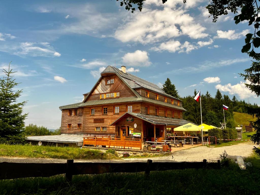 a large wooden building with a restaurant in front of it at Horský hotel Portáš in Nový Hrozenkov