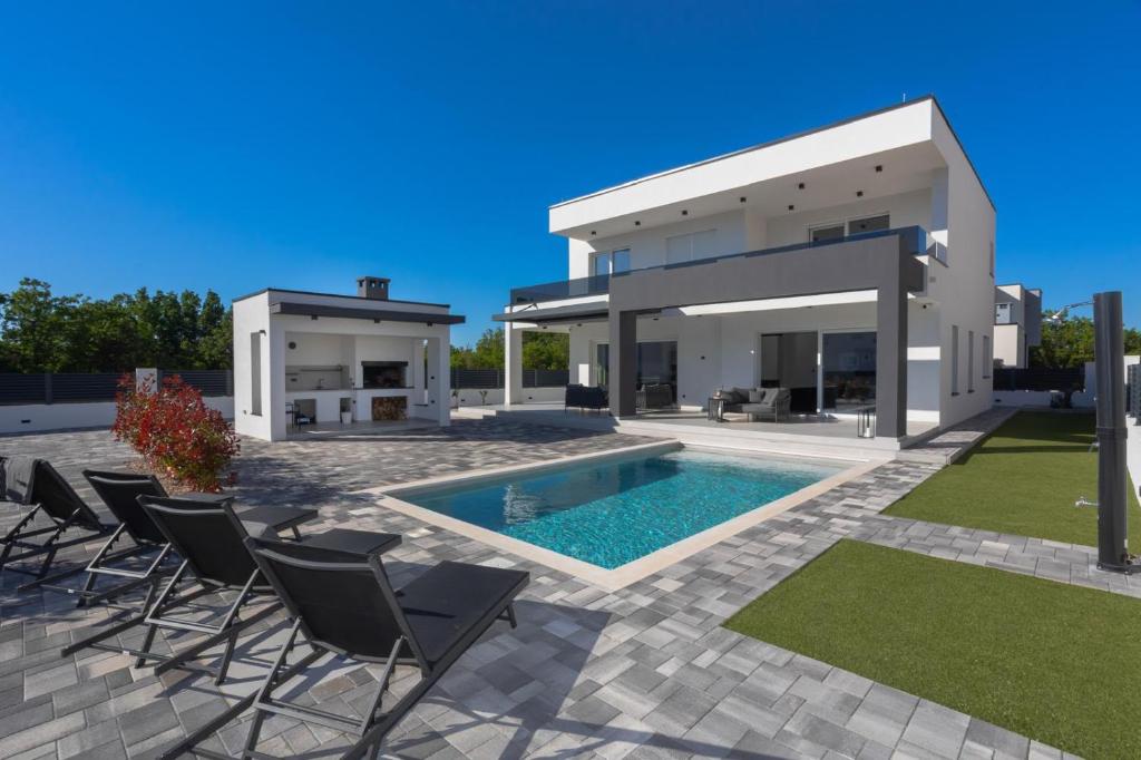 a house with a pool and chairs in front of it at Villa della Rode in Lozovac