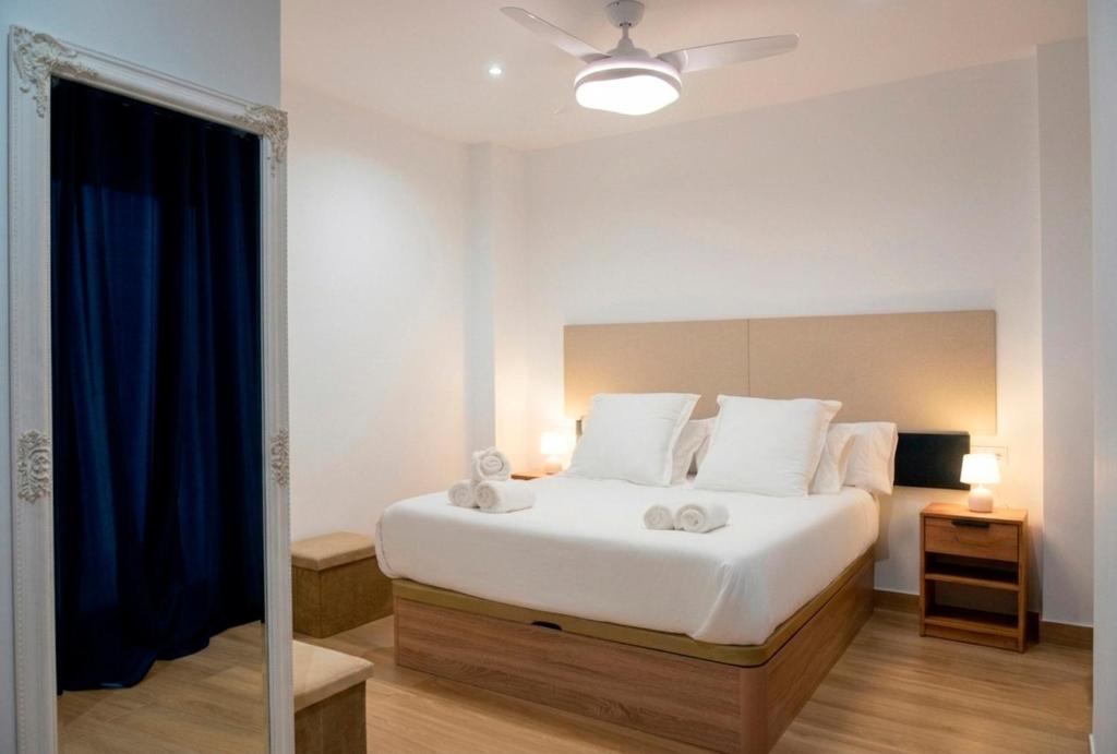 a bedroom with a white bed and a blue curtain at Apartamento Menacho in Badajoz