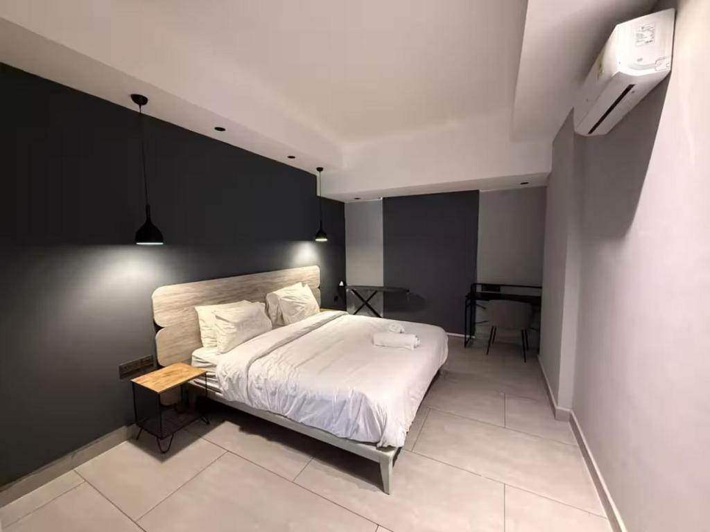 a bedroom with a white bed and a table at QUATTRO-Sky Suites in Accra