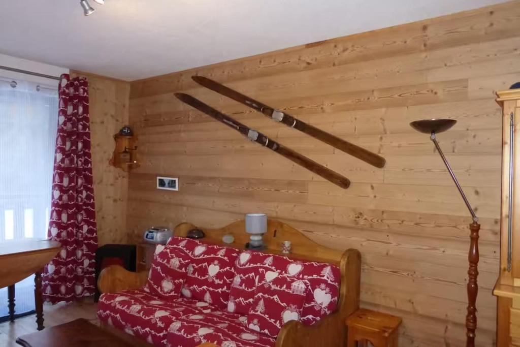 a living room with a red couch and wooden walls at Studio with mountain view in Barcelonnette in Barcelonnette