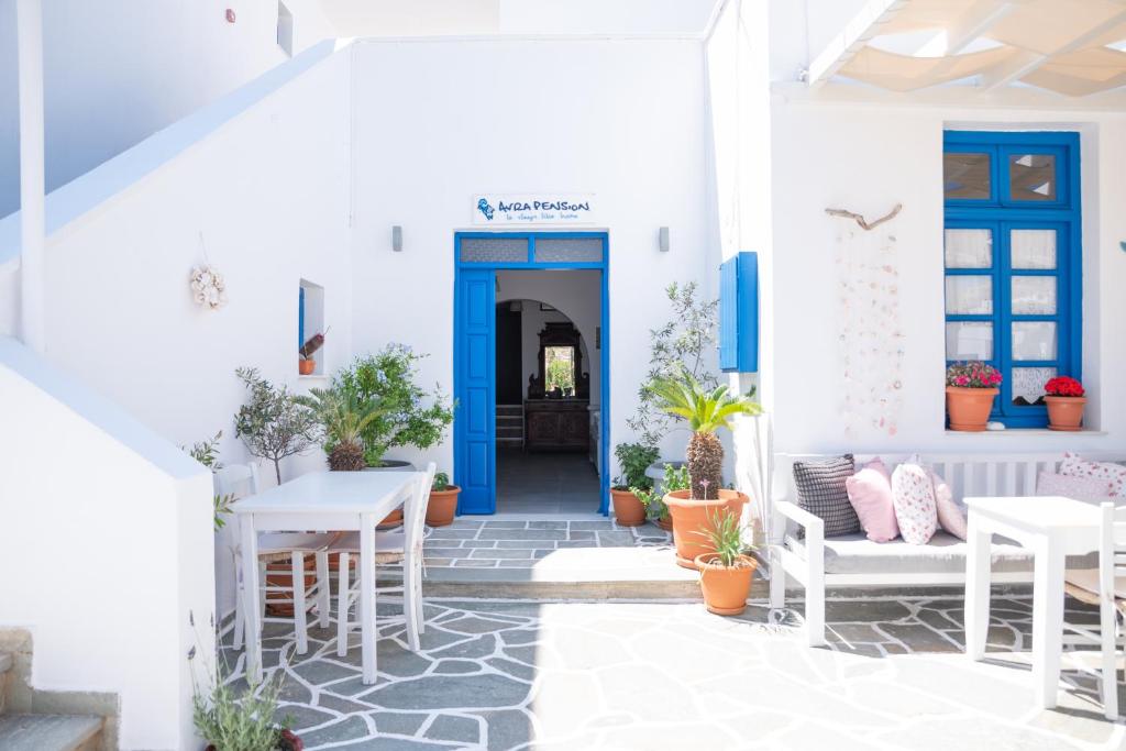 a white house with blue doors and tables and plants at Avra Pension in Ios Chora