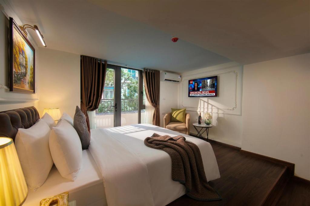 a bedroom with a large white bed and a television at Bastra Classy Hotel in Hanoi