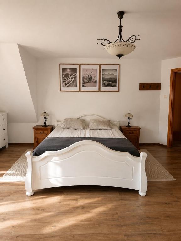 a white bed in a white bedroom with a chandelier at Apartament u SKOCZKA in Poronin