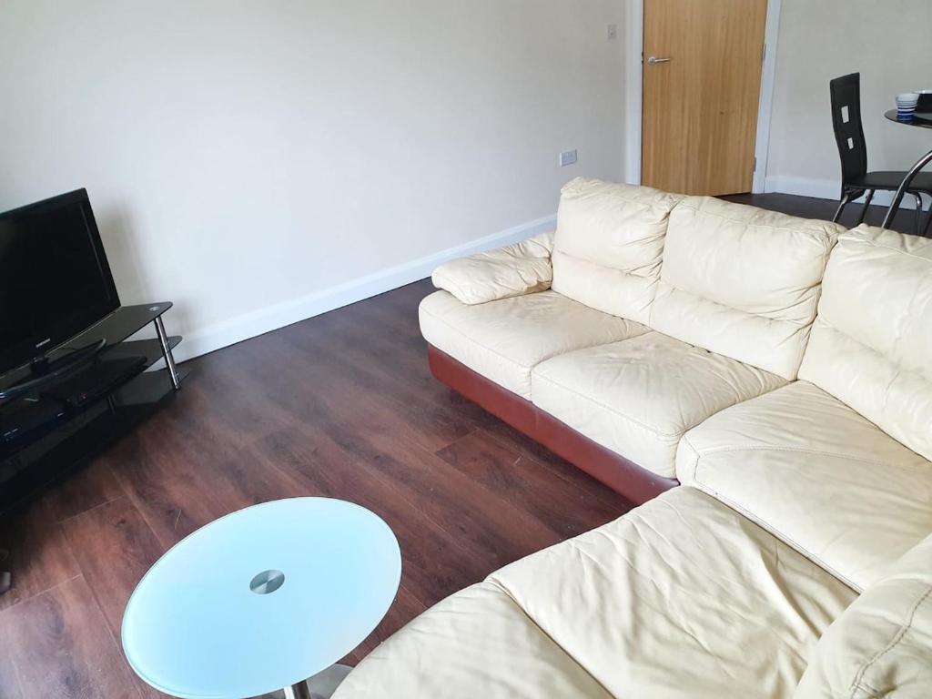 a living room with a white couch and a table at Double room in a shared 2bed flat in Milton