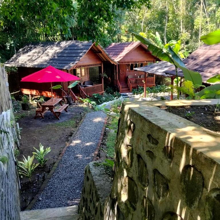 a house in a forest with a stone wall at Gecko Lodge in Tetebatu