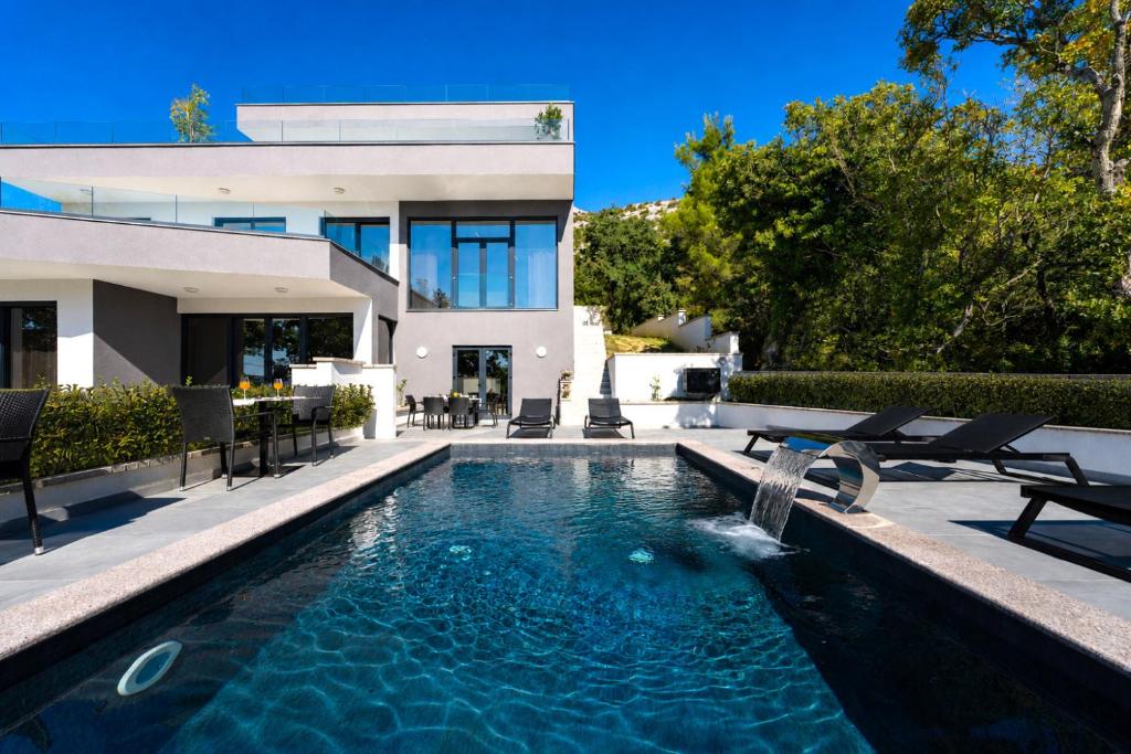 a swimming pool in front of a house at My Dalmatia - Sea View Villa Senti with private pool in Starigrad