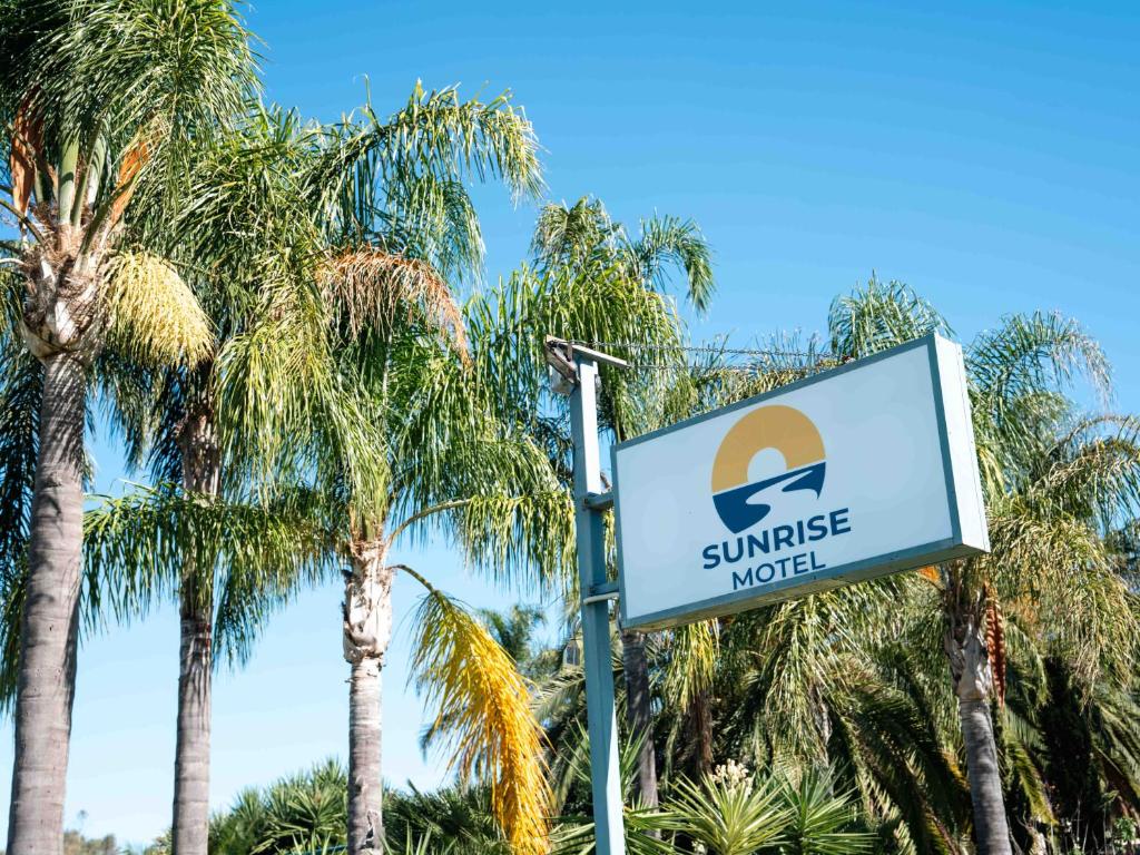 a sign for a sunrise motel in front of palm trees at Sunrise Motel in Barooga