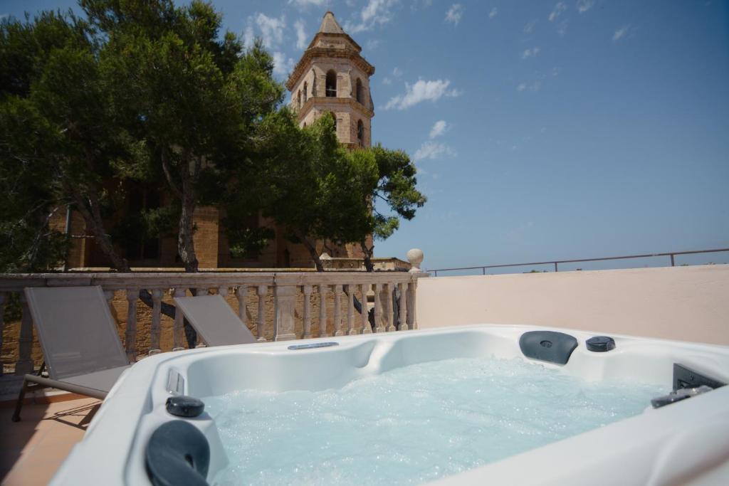 a bath tub on a balcony with a clock tower at Bytra Boutique Hotel - Adults Only in Petra