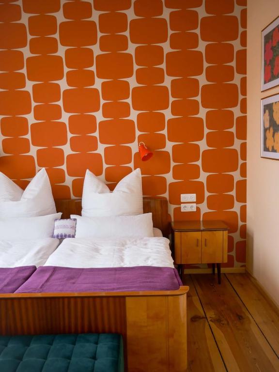 a bed in a room with an orange wall at Das Wilde 70er in Dobritz