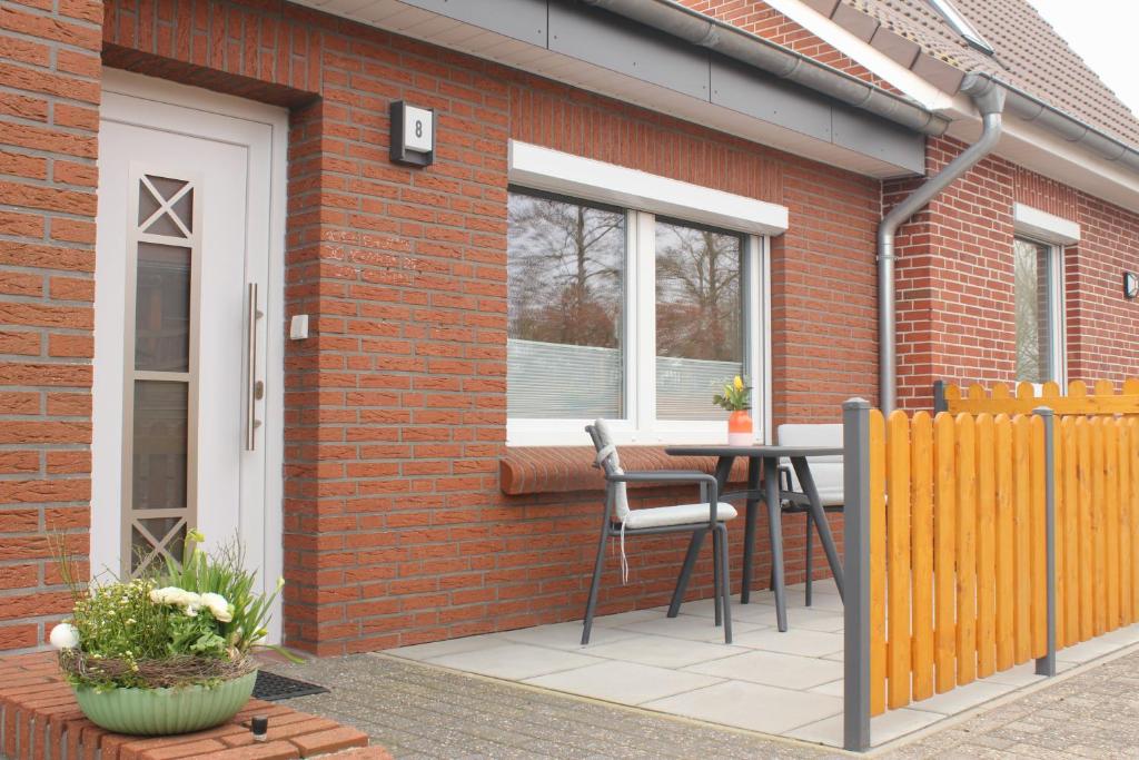 a patio with a table and a chair next to a brick building at Ferienwohnung "Lüttje Koje" in Barßel