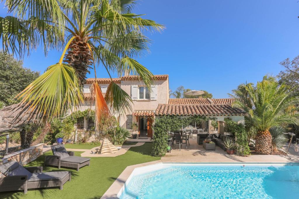a house with a palm tree and a swimming pool at Maison avec piscine Soleil d'Azur in Fréjus