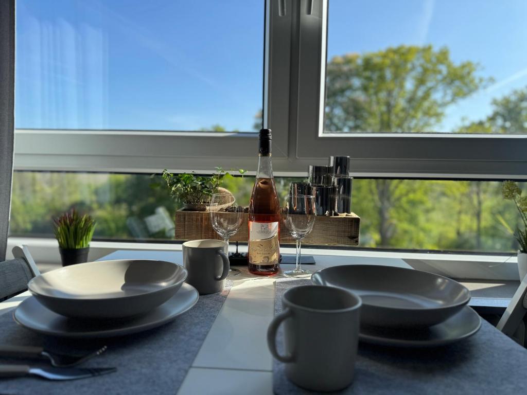a table with plates and a bottle of wine and a window at Appartement Briesenick-Radde in Tossens